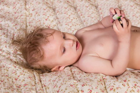 可爱的金发宝贝女孩美丽的蓝眼睛，躺在床上的玩具