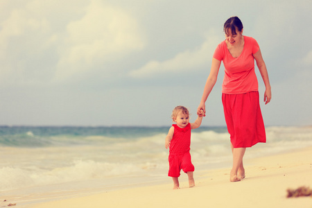 在沙滩上散步的小女儿和妈妈