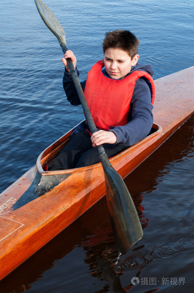 男孩在皮艇在河上划船