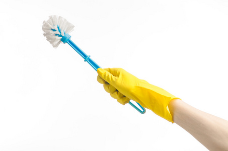 打扫房间和清洗厕所 人的手里孤立在工作室中的白色背景上的黄色防护手套拿着蓝色的马桶刷