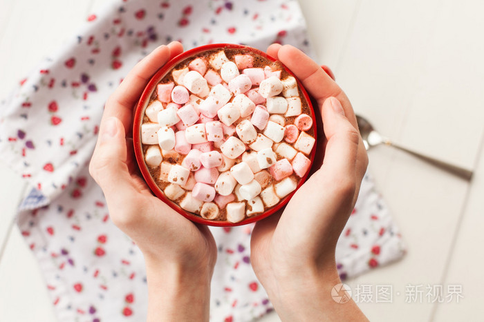 手里捧着杯子里的热巧克力和果汁软糖