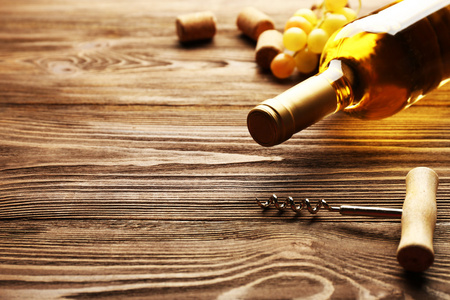 玻璃带瓶葡萄酒软木塞，开瓶器和葡萄在木桌背景