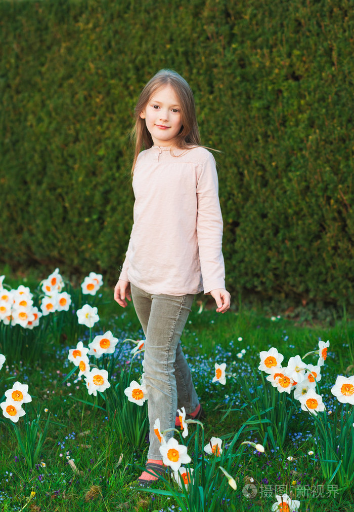 可爱的小女孩,7 岁之间水仙花花春天公园里玩的