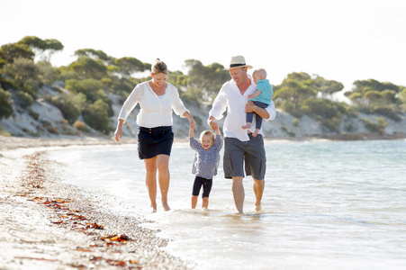 年轻快乐美好的家庭享受暑假的海滩上散步，一起