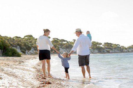 年轻快乐美好的家庭享受暑假的海滩上散步，一起
