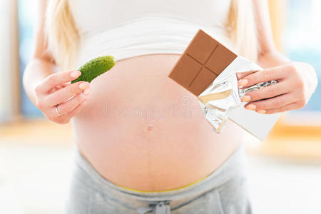 孕妇拿着腌菜和巧克力