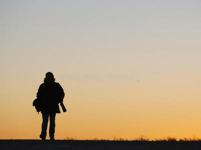 一个男人走在路上，在夕阳下照着背光