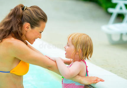 快乐的妈妈和小女孩在游泳池里