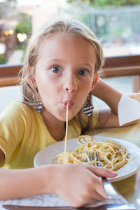 可爱的小女孩在户外吃意大利面