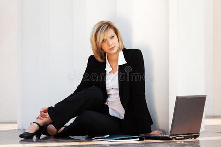 坐在墙上的年轻女商人拿着笔记本电脑