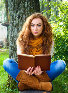 姜黄色头发的女人坐在长椅上看书