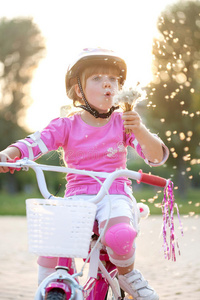 戴着粉红色安全帽的女孩骑着自行车吹着d