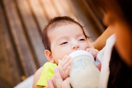 妇女用儿童小瓶子喂婴儿的图像