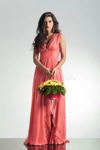 时尚的年轻女子，穿着优雅的红色连衣裙，手里拿着花篮
