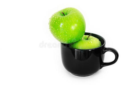 白色背景上黑色陶瓷杯中的新鲜绿色苹果