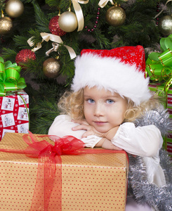可爱的小女孩戴着圣诞帽，带着圣诞礼物