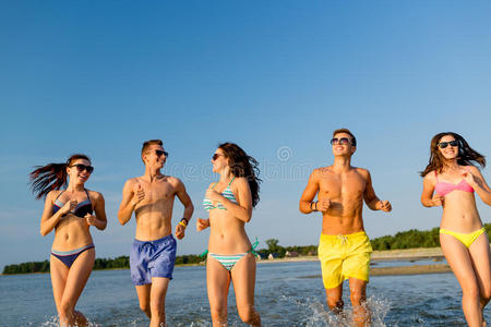 戴着墨镜微笑的朋友在沙滩上奔跑
