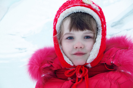冬天在相机看的小快乐的女孩，在红色暖和的衣服