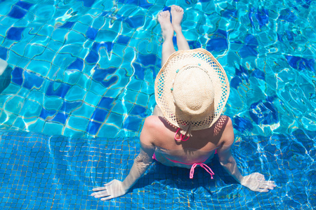 年轻漂亮的女人，在温泉泳池中放松的草帽