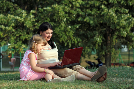 快乐的女孩和孩子在公园里的笔记本电脑