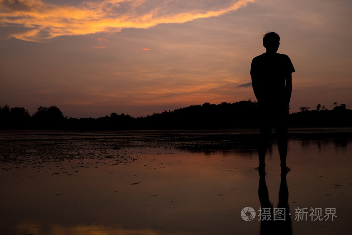 与水中倒影在日落海滩上的人