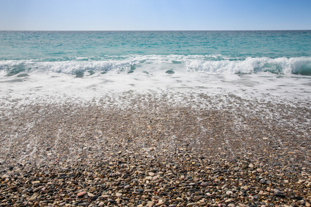 海波浪泡沫在卵石的海滩上
