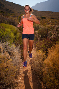 金发碧眼的女径赛跑者贯穿一个山风景