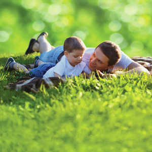 夏季照片快乐父亲和儿子在一起躺在新鲜绿色
