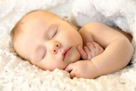 新生女婴平静地睡在白色的毯子