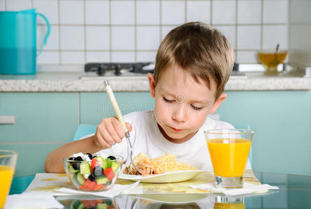 男孩在桌子边吃东西，看着盘子横着