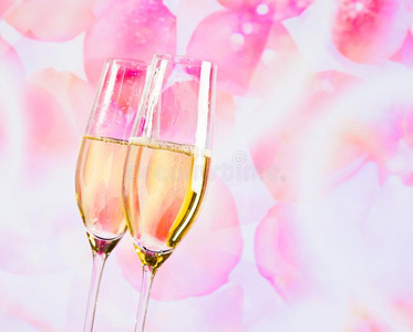 在模糊的玫瑰花瓣背景上有金色气泡的香槟长笛