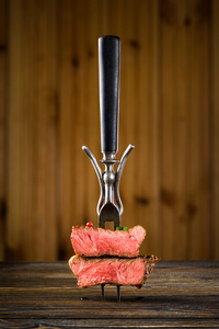 在木桌上的叉子上切牛肉牛排