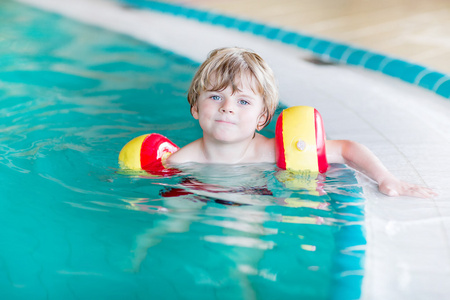 swimmies 学习在室内游泳池游泳的小小孩男孩