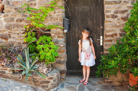 夏天的一个可爱的小女孩，站在老木门的肖像
