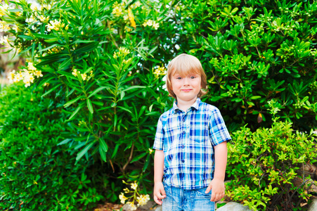 一个可爱的小男孩，身穿蓝色格子衬衫的室外肖像