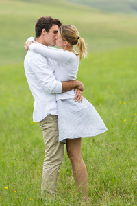 年轻的夫妇在绿色的原野上接吻