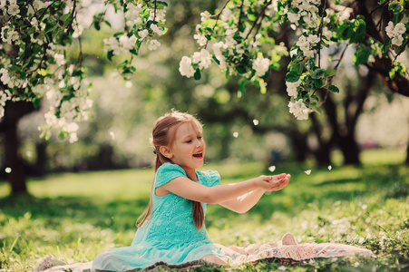 快乐的孩子女孩玩在春天盛开的苹果花园