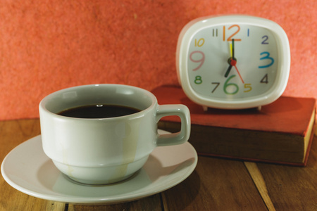 每天早上喝咖啡时钟和一本书，木制的桌子上。工艺科洛