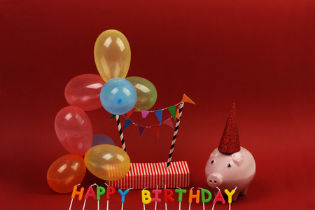 太阳镜上红色的帽子储钱罐用太阳镜生日快乐, 党的帽子和红色背景上的