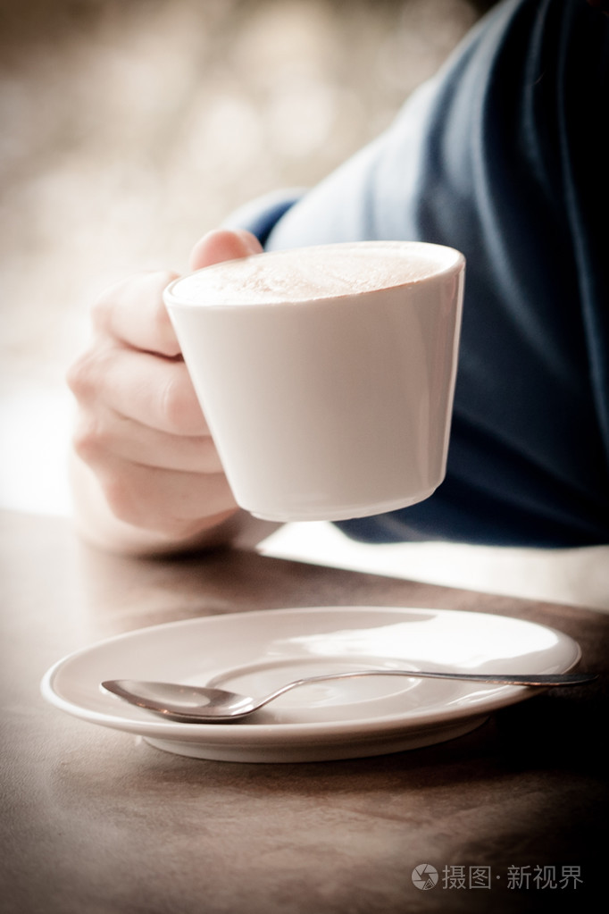 在木桌上的拿铁咖啡与女人手