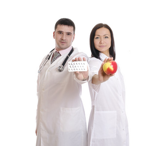 男性和女性的医生拿着苹果和丸股票图像