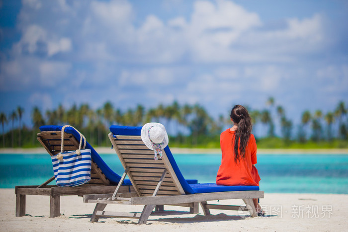年轻女人放松在沙滩椅后面观