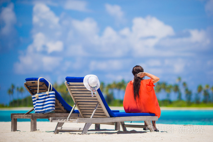 美丽的年轻女子在沙滩躺椅放松肌肉