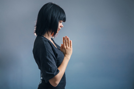欧洲外观黑发女人被蒙上了她的手在祷告