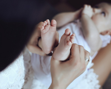 母亲与她合影小可爱的宝贝，手里拿着她的脚