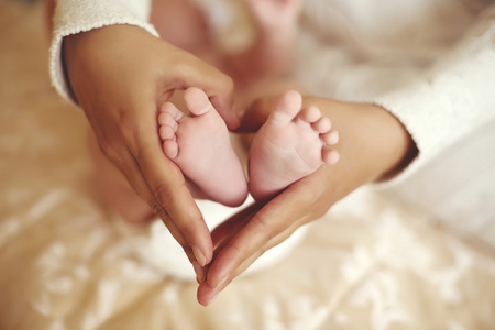 在妈妈手中可爱的宝宝脚的投标内部照片