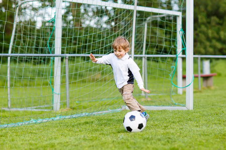 在场上踢足球和足球的两个小兄弟男孩照片