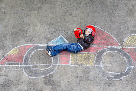 小男孩玩的愉快和赛车用粉笔绘制