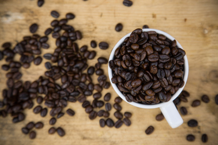 喝咖啡豆背景上木，新鲜的咖啡豆咖啡杯上木制的背景，设置背景