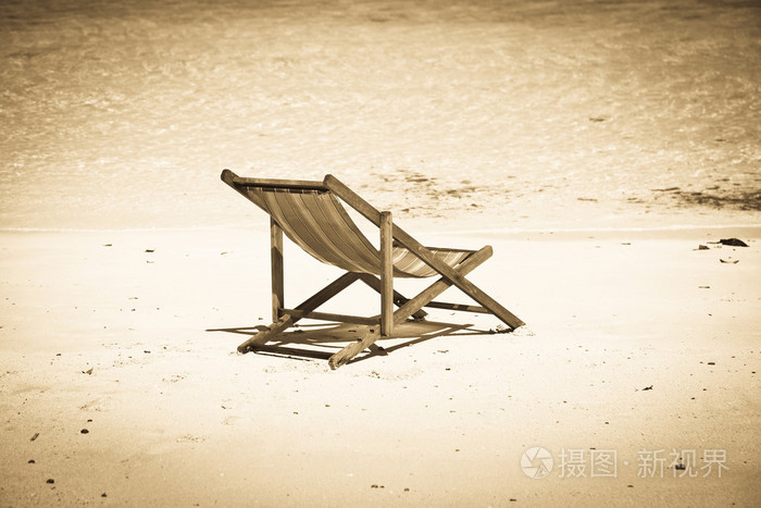 异国风情的沙滩假日背景用白色恨在沙滩椅上